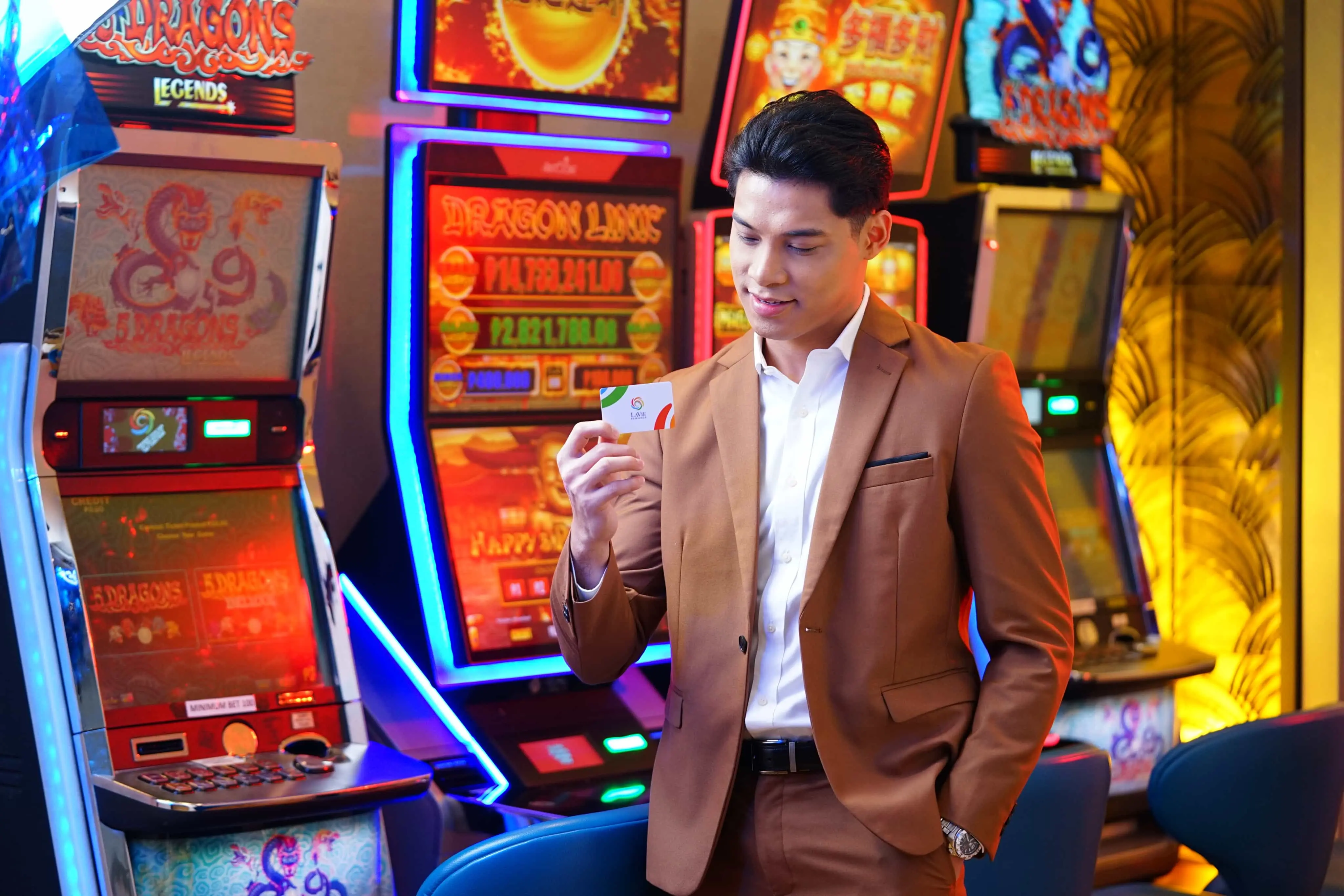 An adult guy happily holding Lavie rewards card at the well-lit Lavie casino